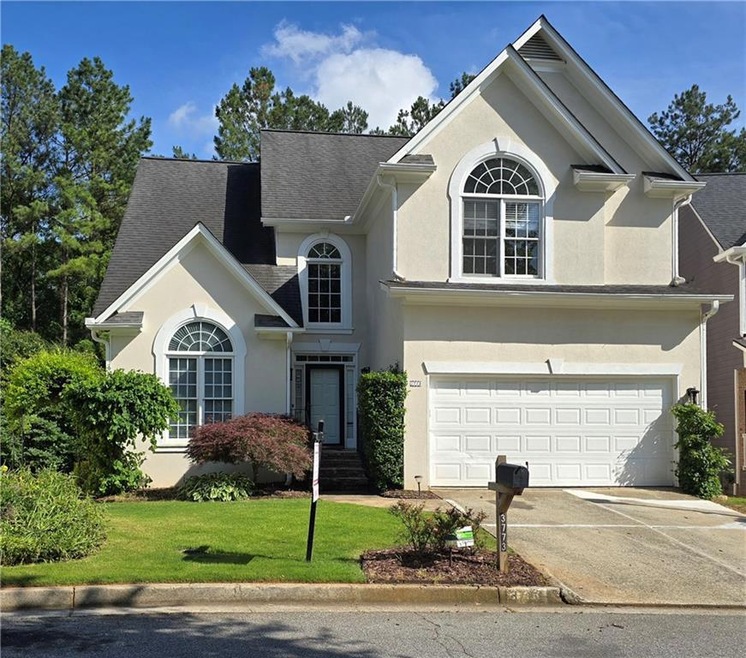 Traditional-style home featuring stucco siding, a front yard, driveway, a garage, and a shingled roof