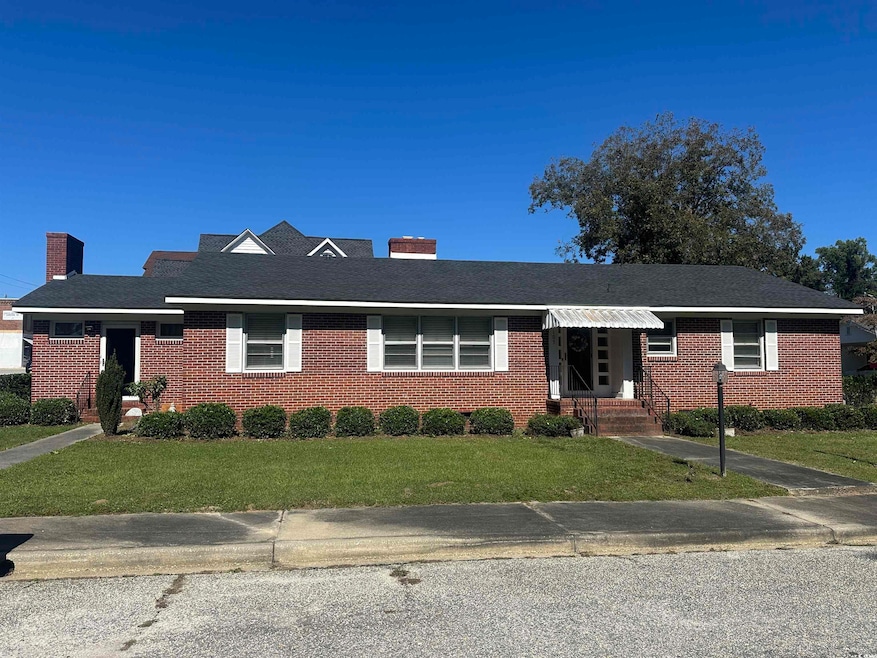 Ranch-style home featuring a front yard, a chimney, brick siding, and a shingled roof