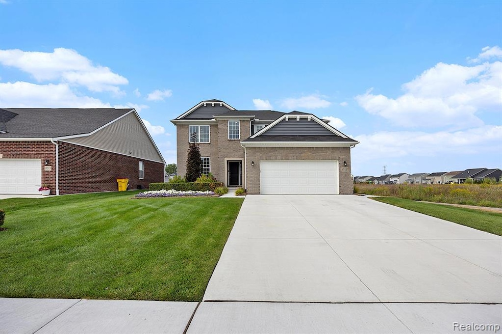 View of front of house with brick siding, a front lawn, driveway, and an attached garage