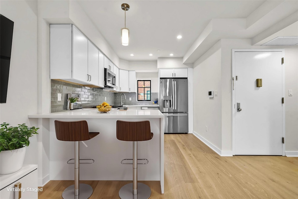 Kitchen with stainless steel appliances, a peninsula, light wood finished floors, light countertops, and recessed lighting