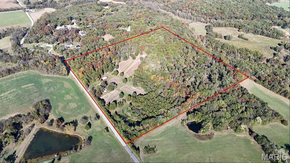 Aerial view of property's location featuring property parcel outlined and a forest
