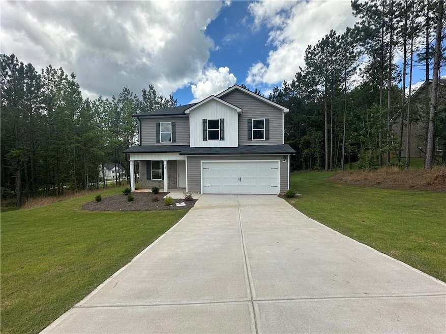 Traditional-style home with concrete driveway, an attached garage, a front yard, and board and batten siding