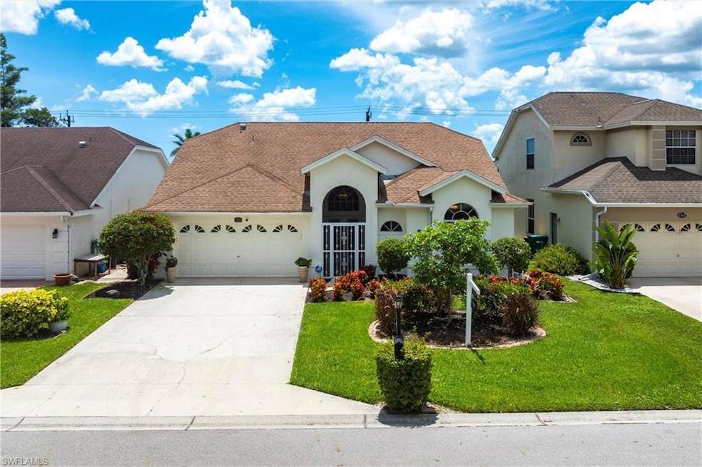 Facade featuring 2 car garage, lush ndscaping, concrete driveway & screened entrance
