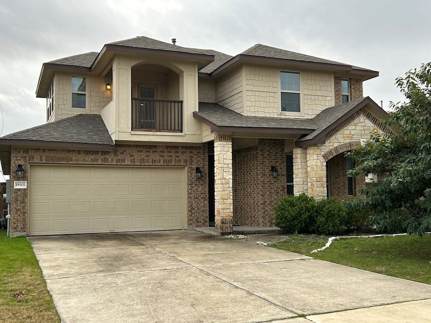View of front of property featuring a balcony, a shingled roof, an attached garage, concrete driveway, and stone siding
