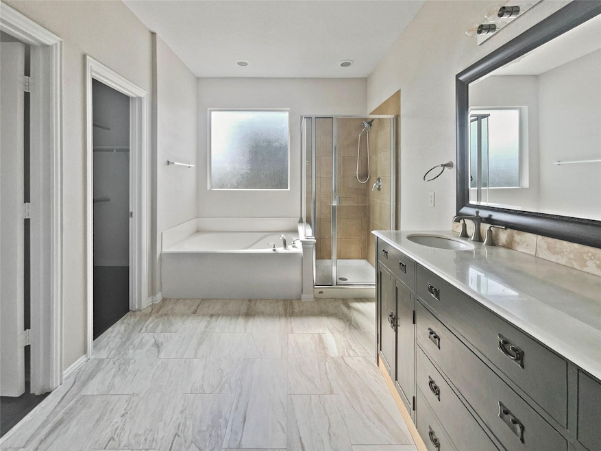 Bathroom with a shower stall, vanity, and a bath
