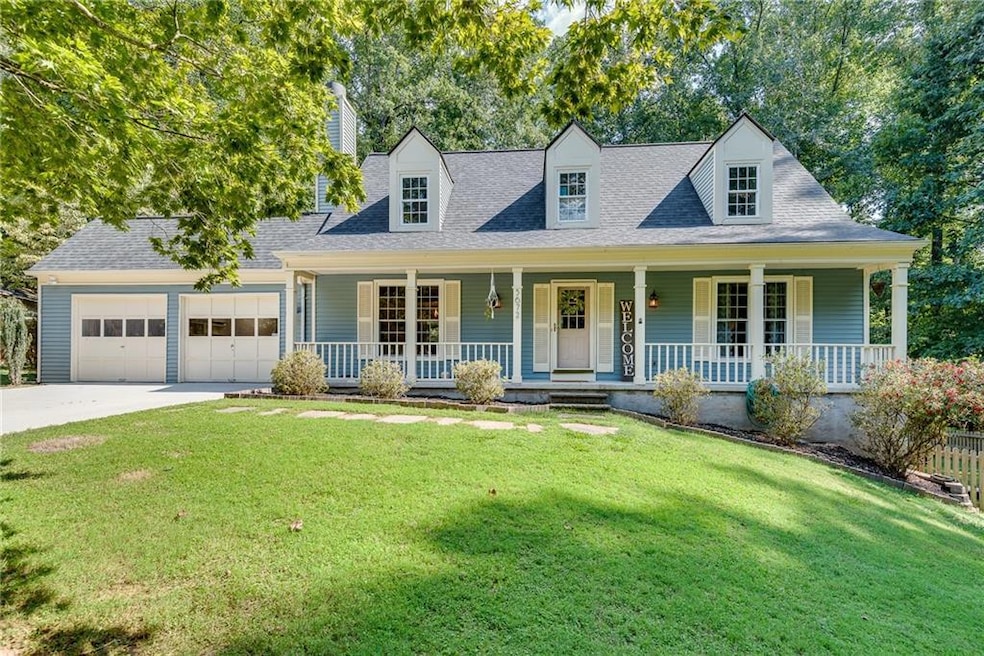 Cape cod home featuring a garage, covered porch, a