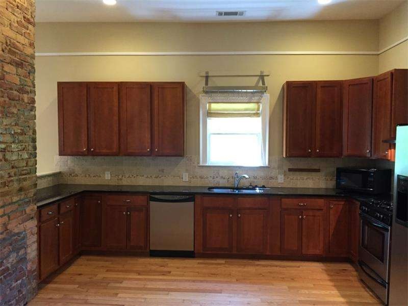 Open kitchen with exposed brick, granite and SS ap