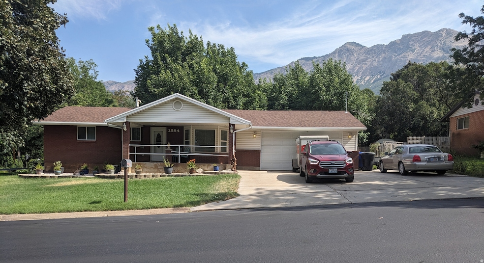 Ranch-style house featuring a mountain view, covered porch, a front yard, and driveway