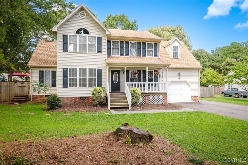 Colonial house with a garage, a front lawn, and covered porch