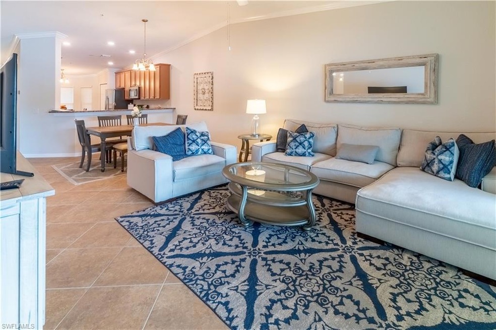 Tiled living room featuring ornamental molding, lofted ceiling, and a chandelier