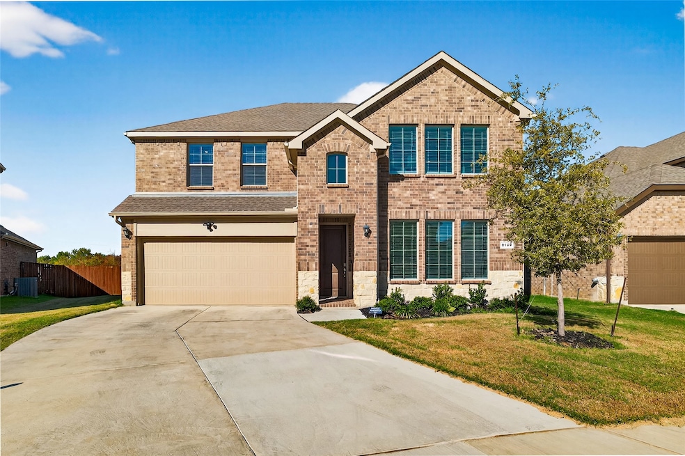 Traditional-style house with roof with shingles, brick siding, driveway, and an attached garage