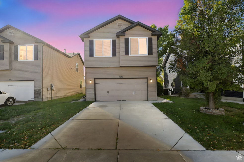 View of front of house with a front lawn, driveway, and an attached garage