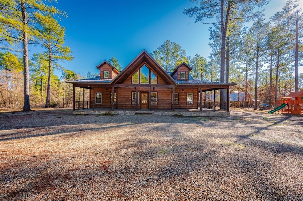 Back of property featuring log veneer siding, playground community, and a porch