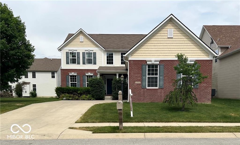 traditional-style home featuring brick siding, concrete driveway, and a front yard