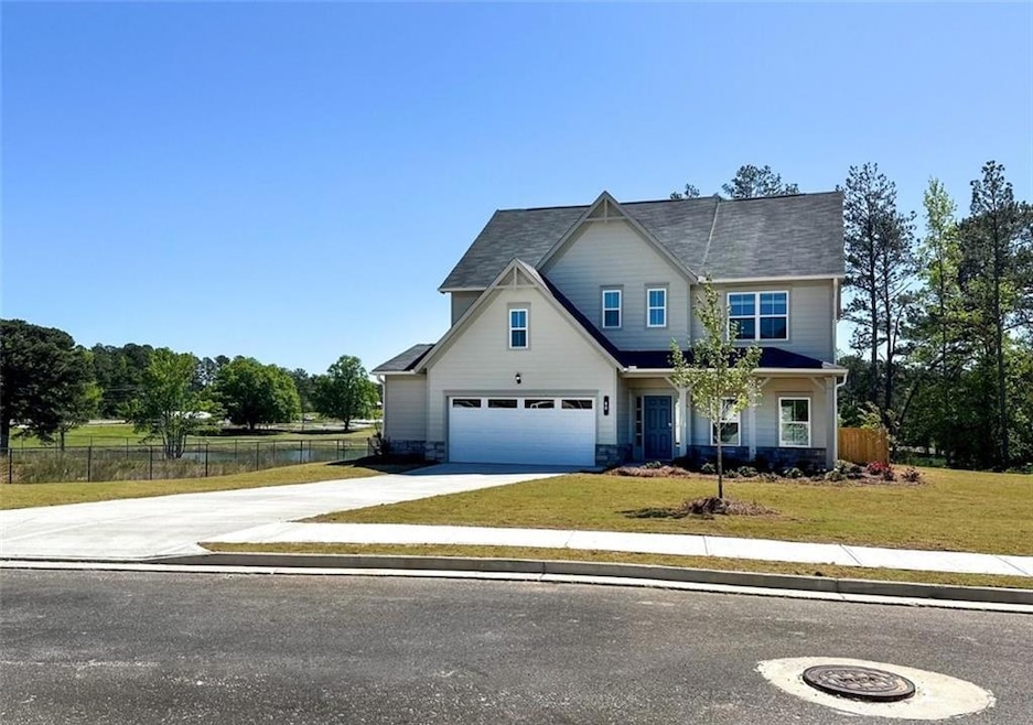 View of front of property featuring concrete driveway, a garage, stone siding, and a water view