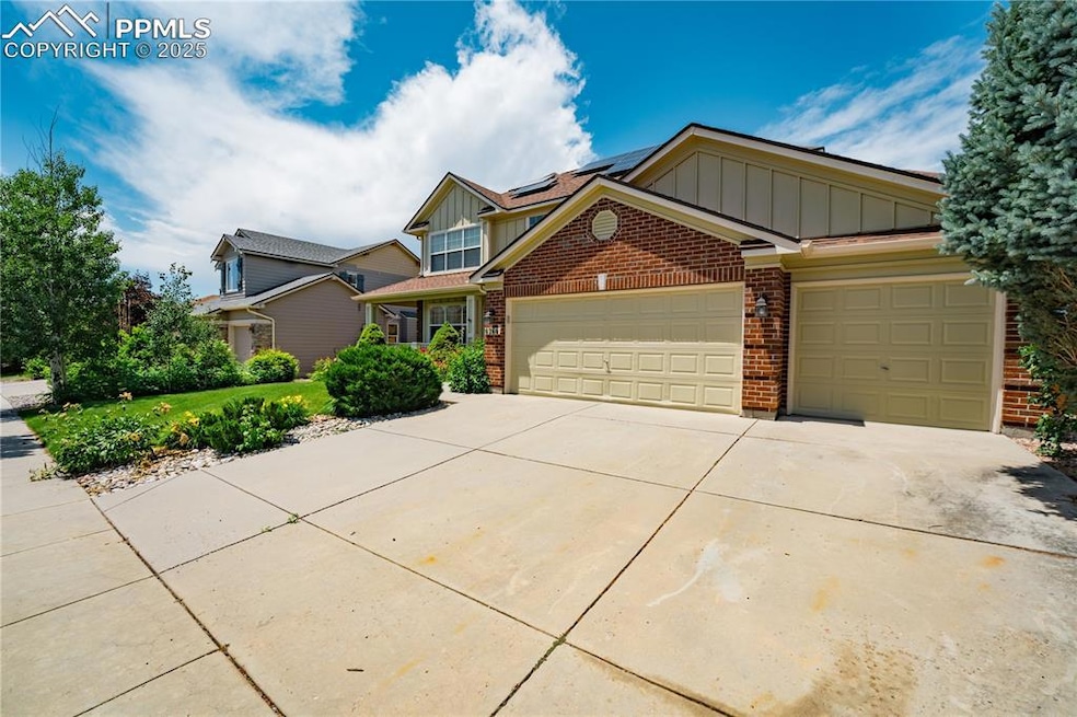 View of front of home featuring board and batten siding, a porch, solar panels, an attached garage, and driveway