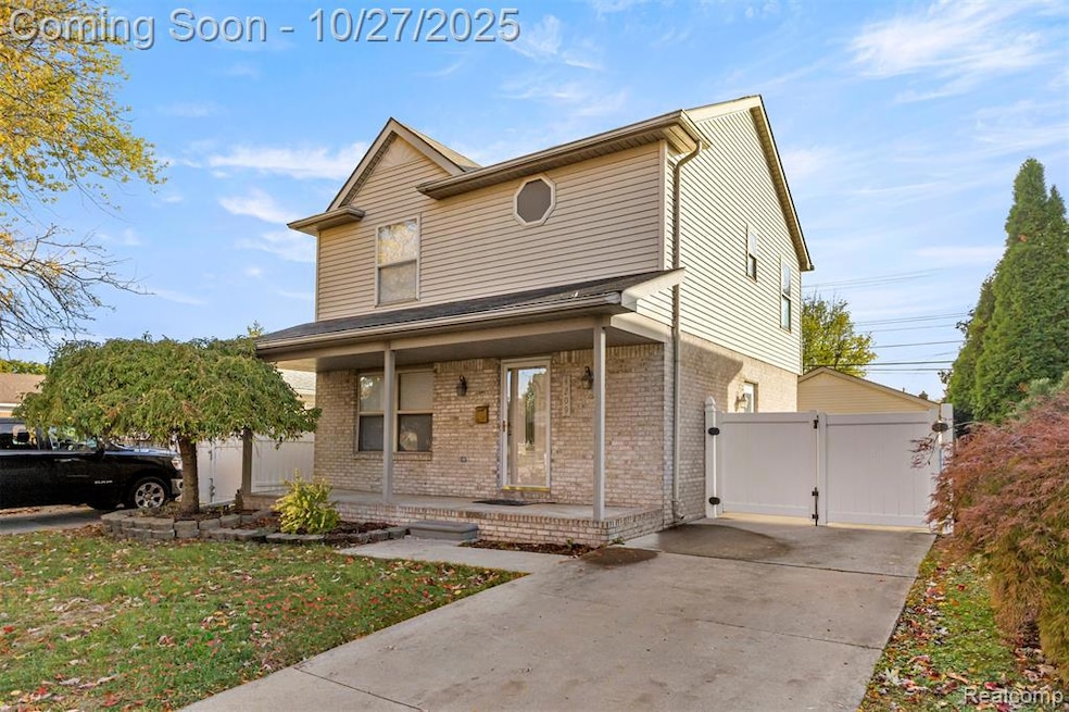Traditional-style home with a porch, a gate, brick siding, and a front lawn