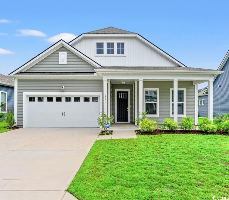 View of front of house featuring a porch, board and batten siding, a front yard, driveway, and an attached garage