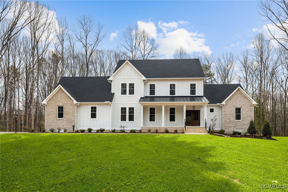 Modern farmhouse style home with board and batten siding, a front yard, covered porch, and brick siding