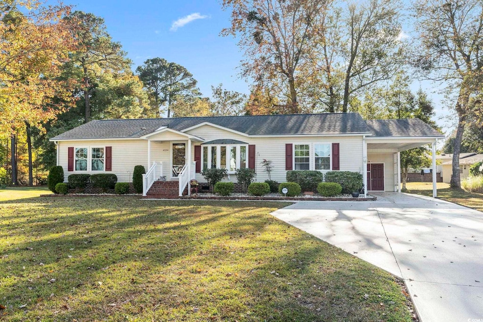 Ranch-style house featuring a front lawn, a carport, and driveway