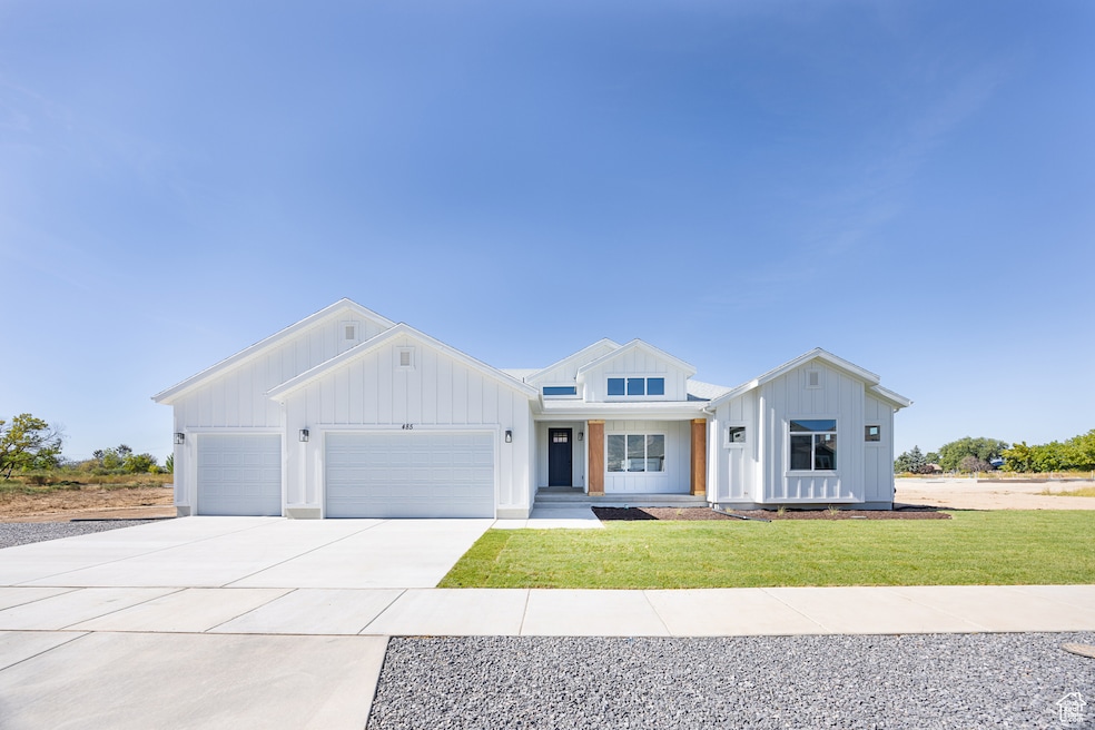 Modern farmhouse style home with board and batten siding, a garage, concrete driveway, and a front lawn
