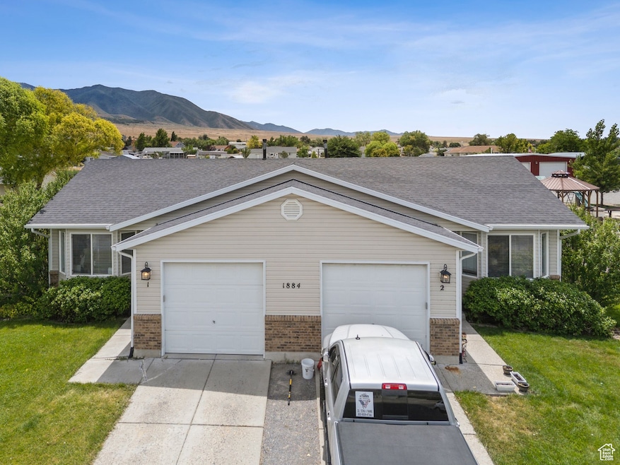 View of front of house with brick siding, driveway, a front yard, and a mountain view