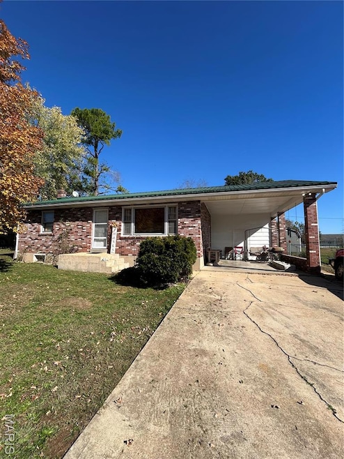 Ranch-style home with brick siding, driveway, an attached carport, and a front yard