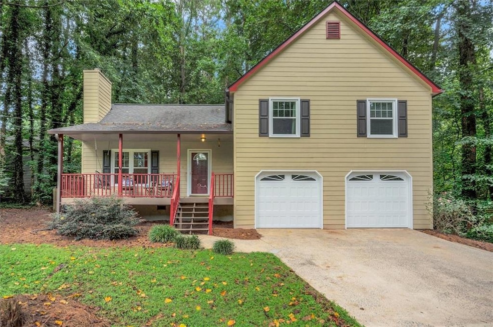 Split-level home with covered porch, a chimney, driveway, a shingled roof, and an attached garage