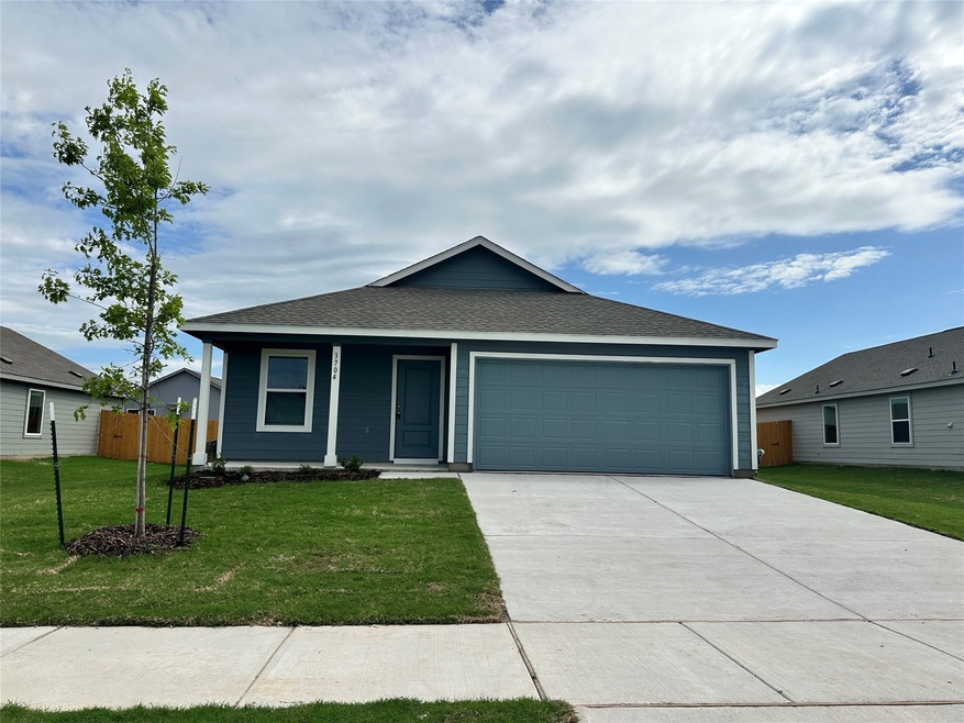 View of front facade featuring a front lawn, driveway, a garage, and fence