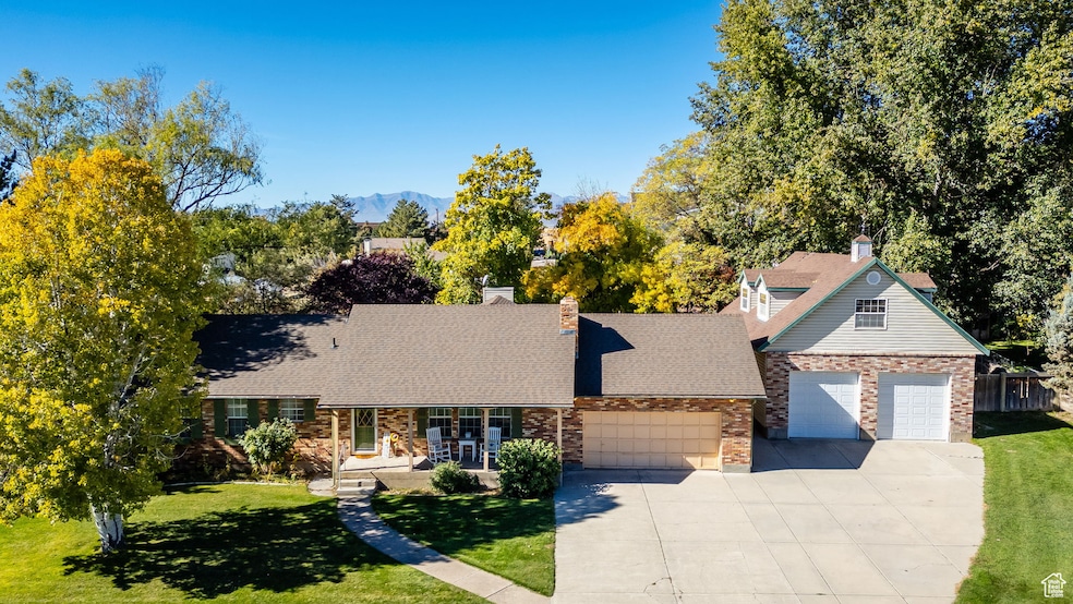 View of front of property featuring a chimney, concrete driveway, and detached garage.