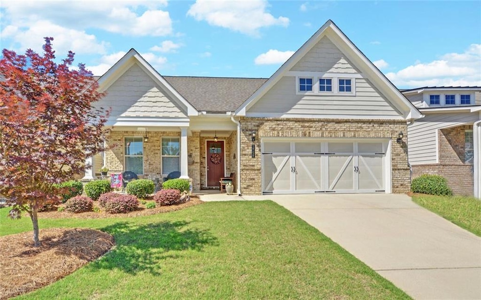Craftsman-style house with brick siding, a front yard, and concrete driveway