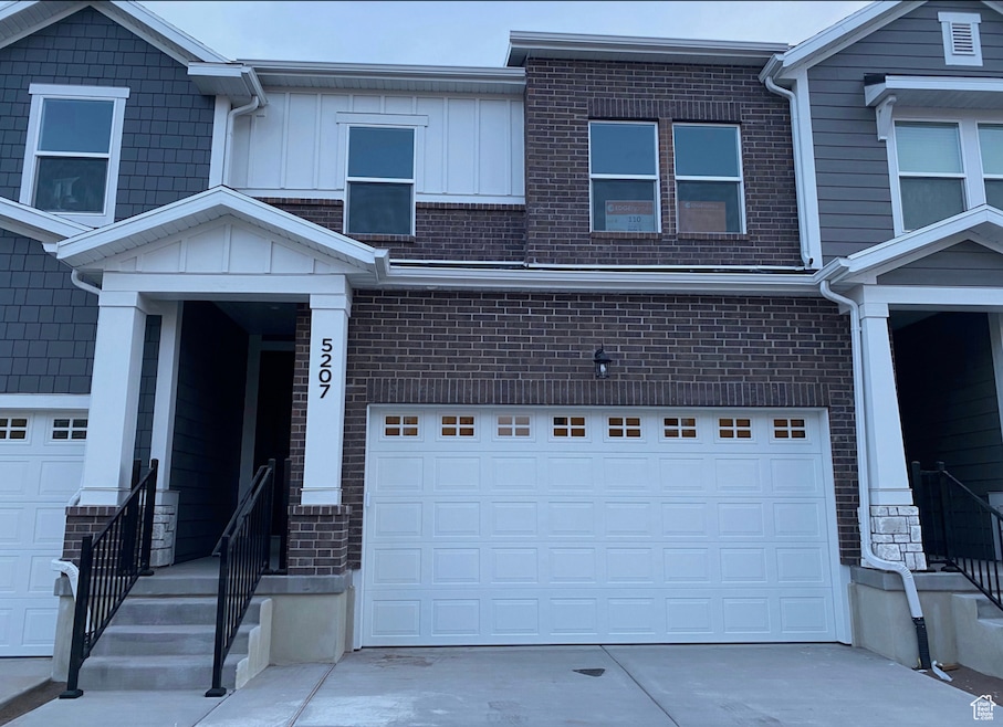 View of front of property with concrete driveway, brick siding, and a garage