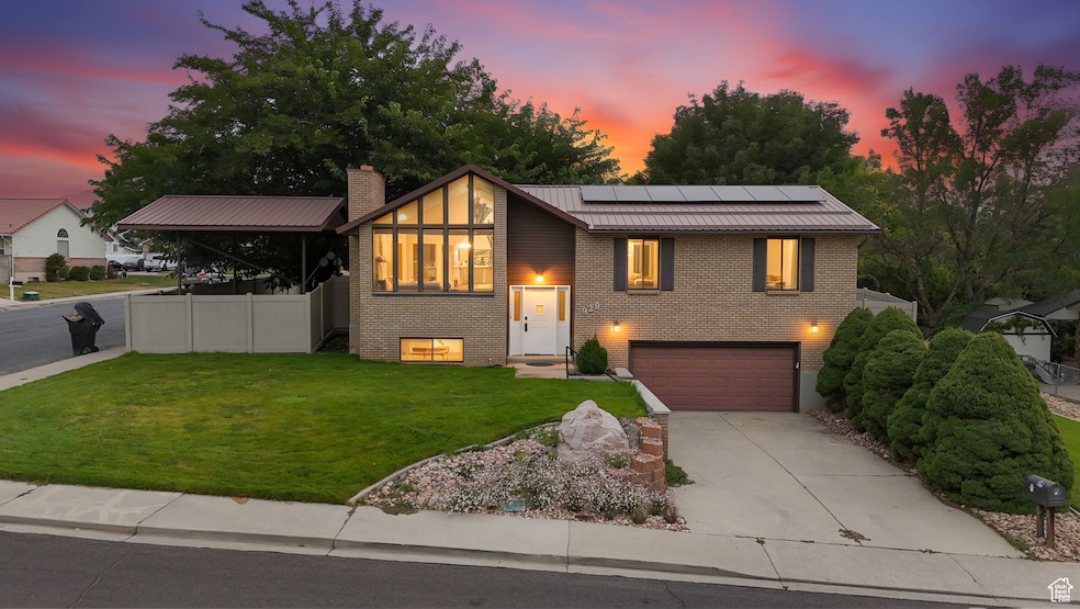 View of front of house featuring roof mounted solar panels, driveway, brick siding, metal roof