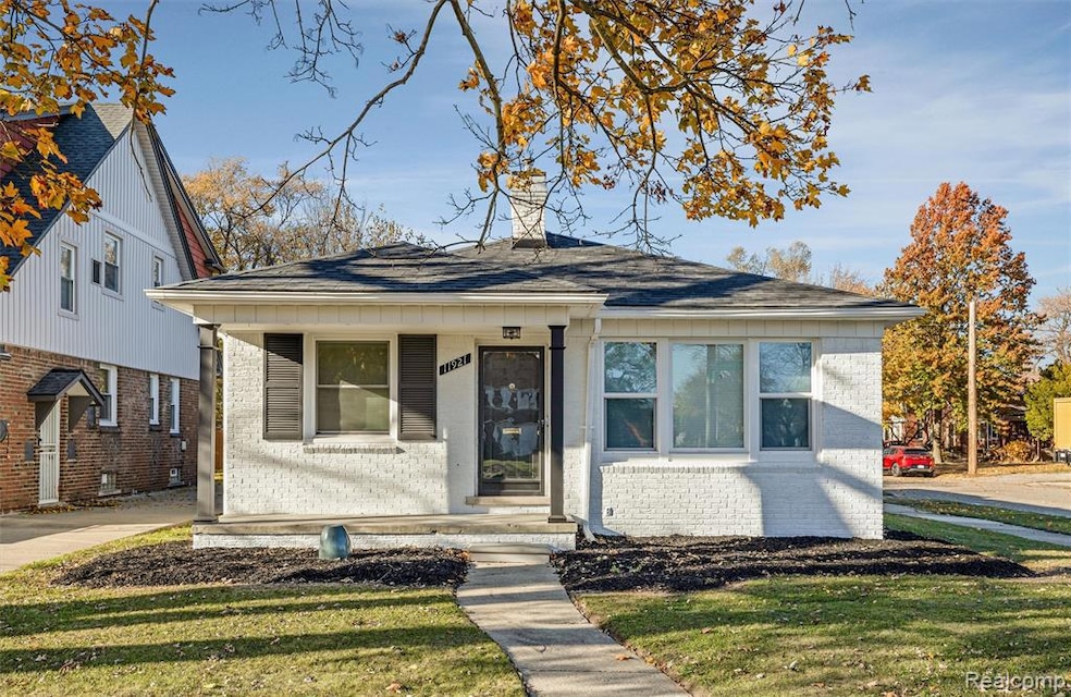Bungalow-style house with brick siding, a front yard, and roof with shingles