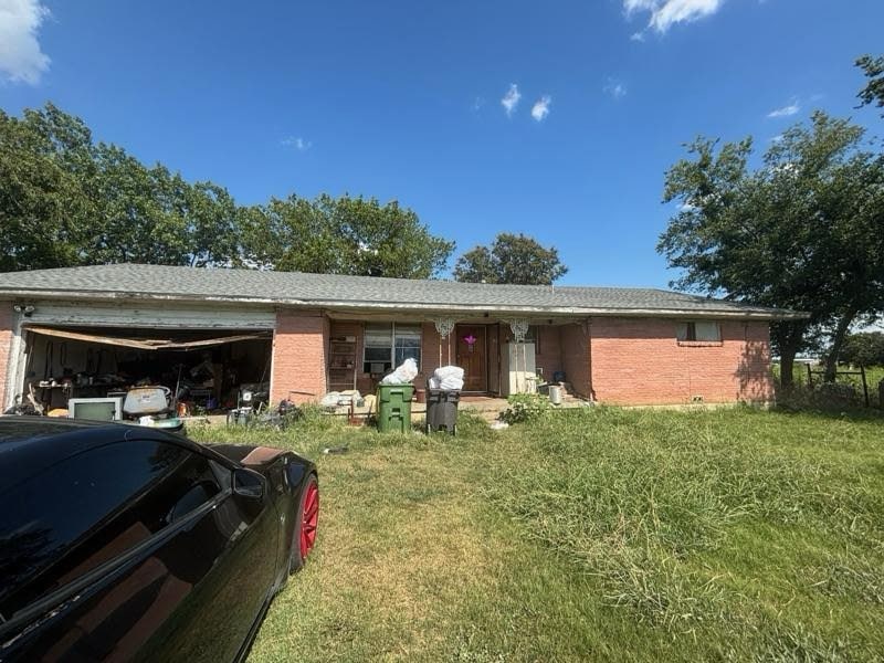 Ranch-style home with brick siding, an attached garage, and a front lawn