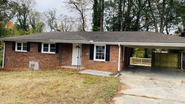 Ranch-style house featuring a front yard, brick siding, concrete driveway, and a carport