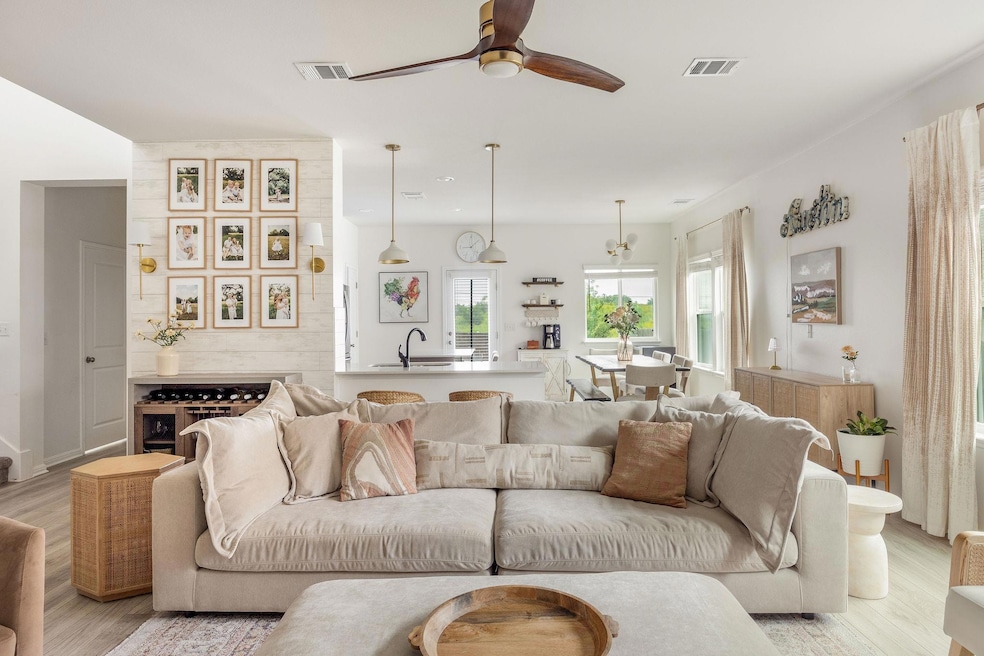 Living area with a ceiling fan, visible vents, an