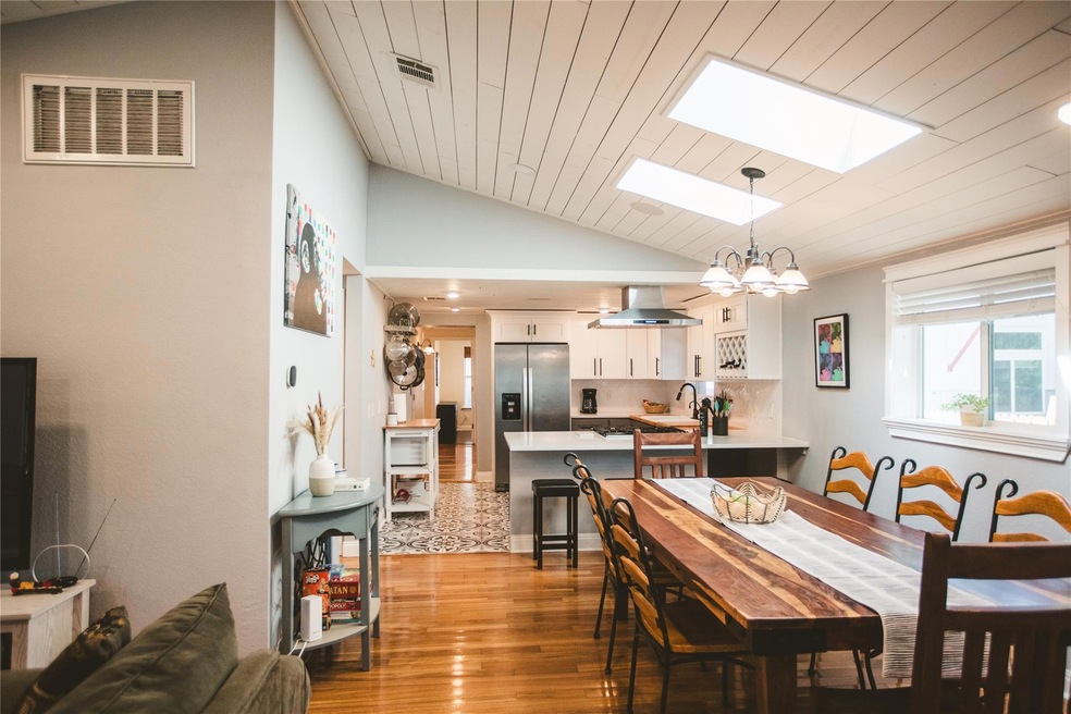 Dining room featuring a chandelier, lofted ceiling with skylight, wood finished floors, and visible vents