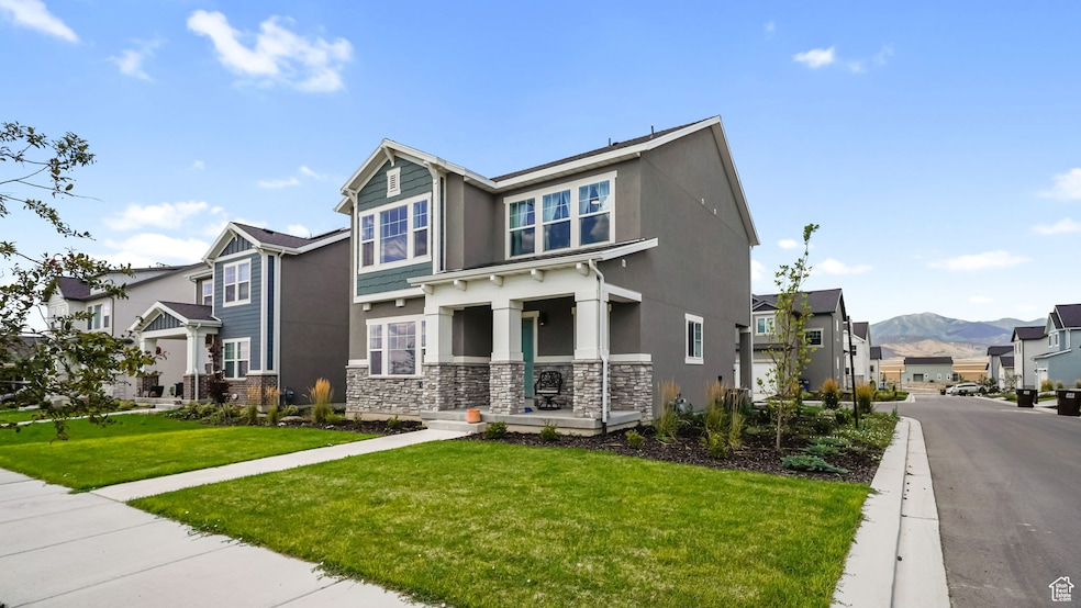 Craftsman-style home featuring a residential view, stone siding, a front yard, stucco siding, and a mountain view