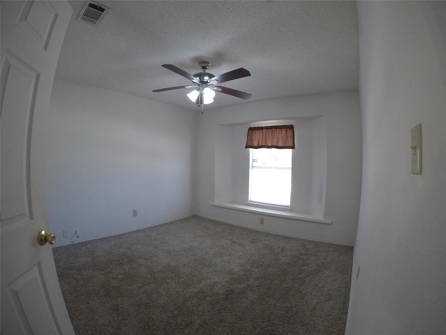 Carpeted spare room featuring ceiling fan and a textured ceiling