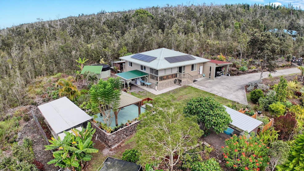 A private retreat with landscaped gardens, solar home, and multiple outbuildings—plus tranquil forest surroundings and small kine ocean views visible from select areas for a touch of island serenity.