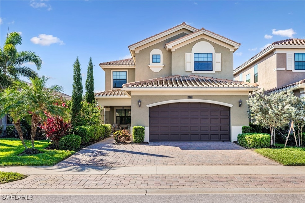 Two-story house featuring a garage, stucco siding, decorative driveway, and a tile roof