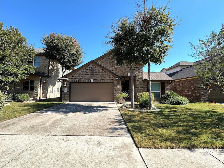 View of front of house featuring concrete driveway, brick siding, a garage, and a front yard