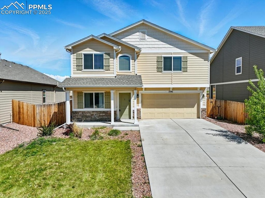 View of front of property with an attached garage, driveway, stone siding, and a porch