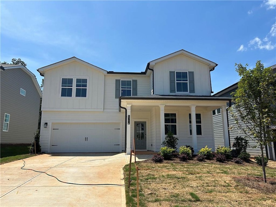View of front of home featuring board and batten siding, an attached garage, concrete driveway, and a porch