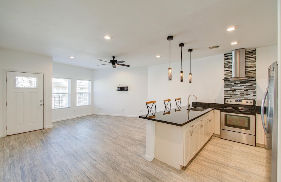 View of kitchen and living area with ample natural light from multiple windows, and a ceiling fan, creating a bright and inviting atmosphere.