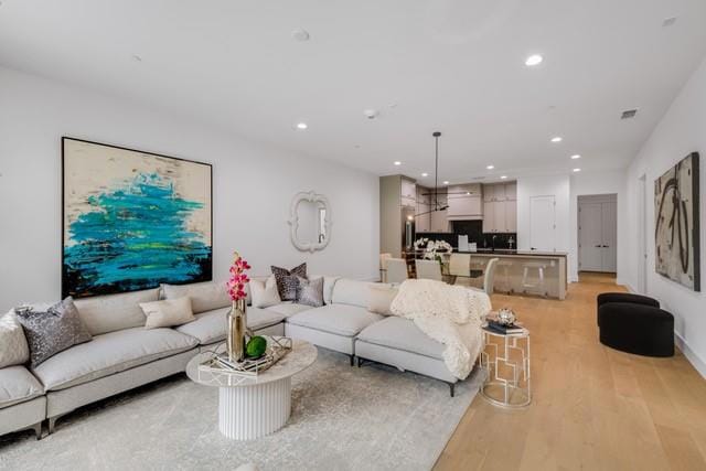 Living room with visible vents, light wood-style f