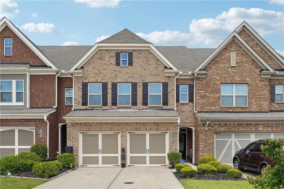 Multi unit property with driveway, brick siding, a garage, and roof with shingles