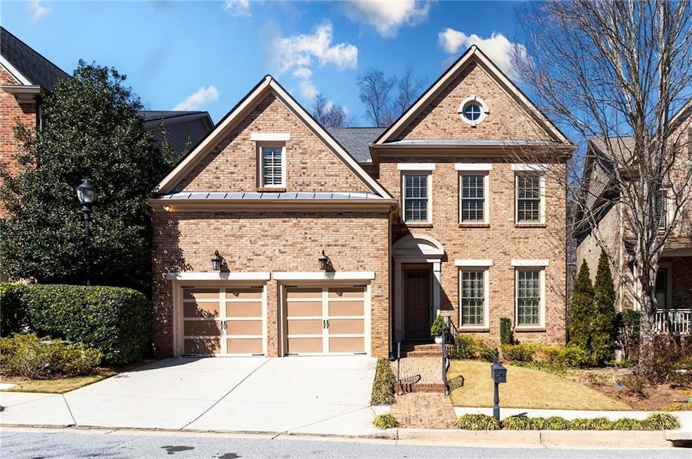 View of front facade featuring a garage, brick sid