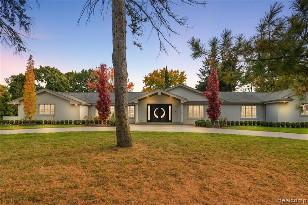Ranch-style house featuring a lawn, stucco siding, and curved driveway